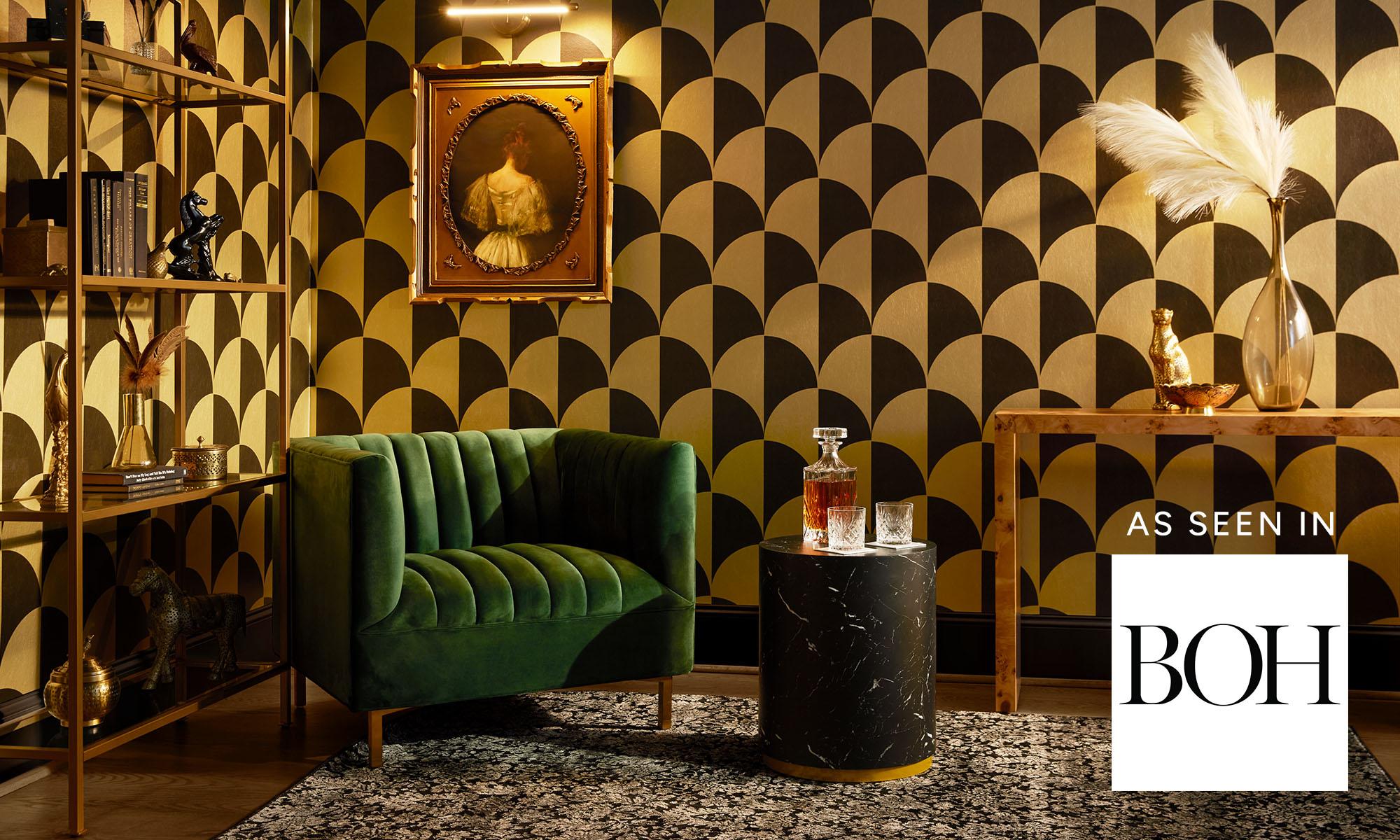 Stylish interior with bold geometric metallic wallpaper, green velvet sofa, marble side table, and vintage decor.