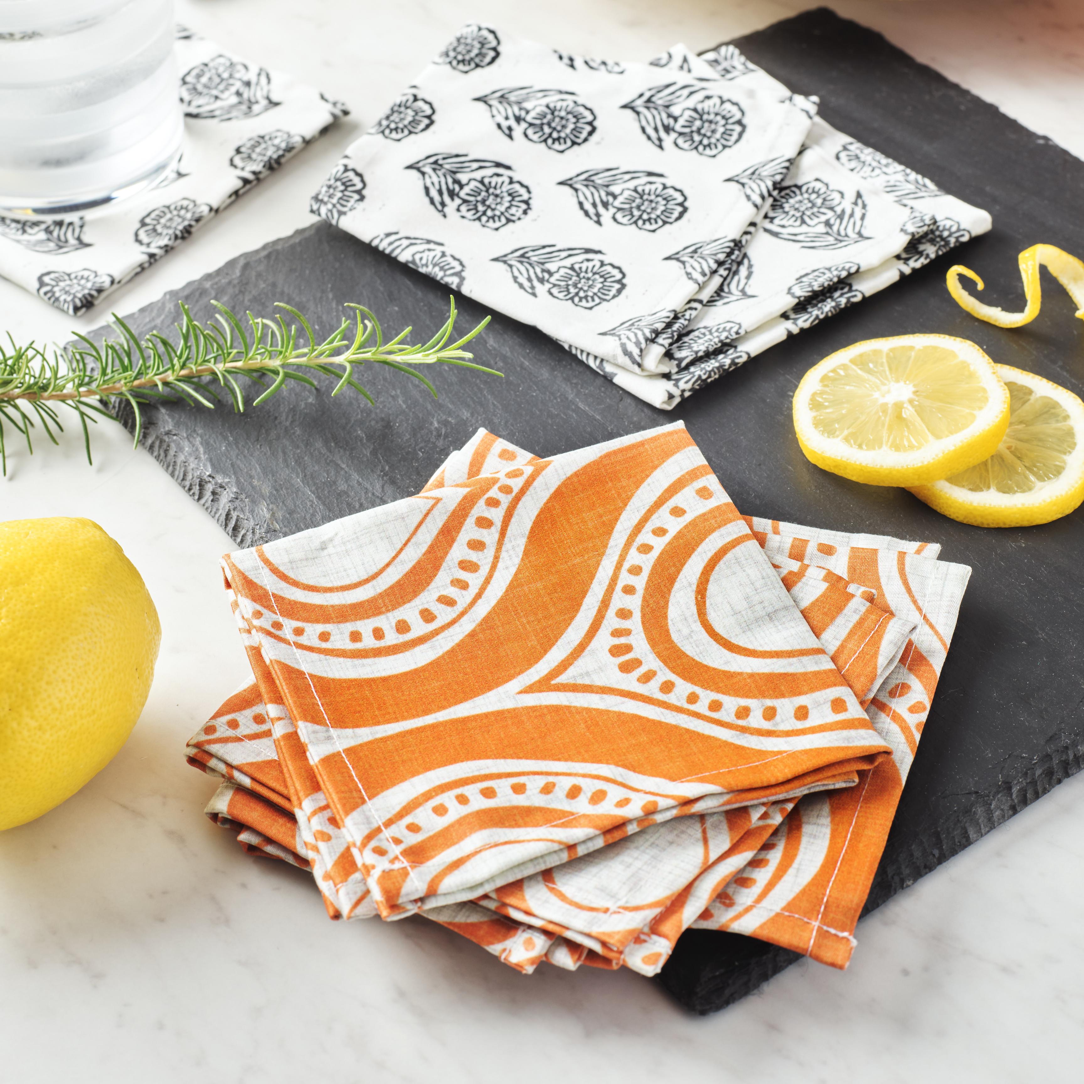 Two sets of cocktail napkins on table with lemon slices