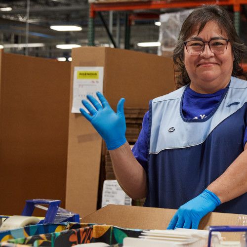 Person waving while working at manufacturing facility