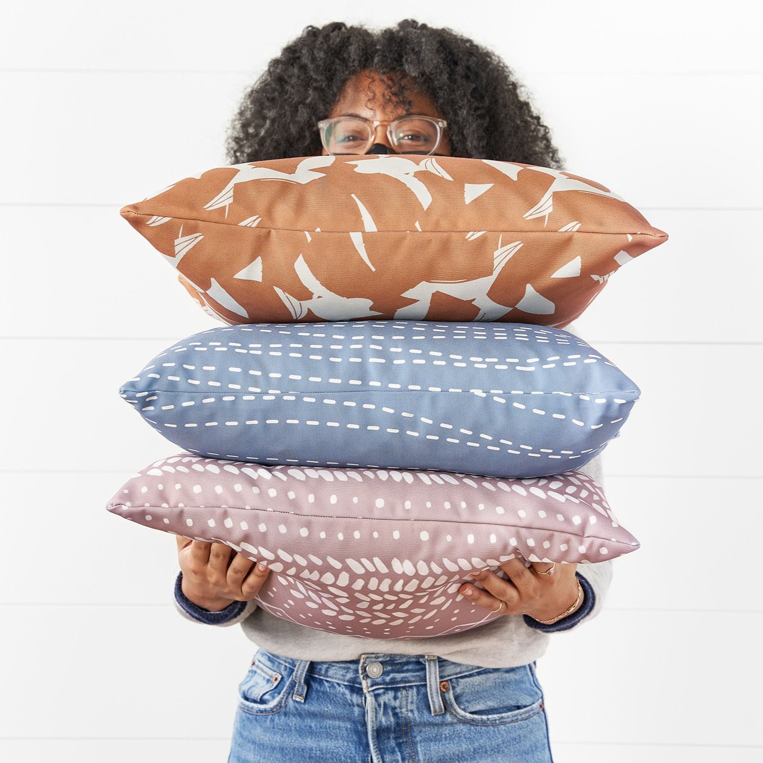 Person holding three throw pillows